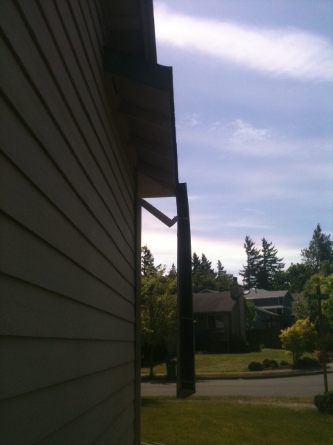 A newly fabricated downspout elbow turning the corner of a Portland home, ready to run down the wall